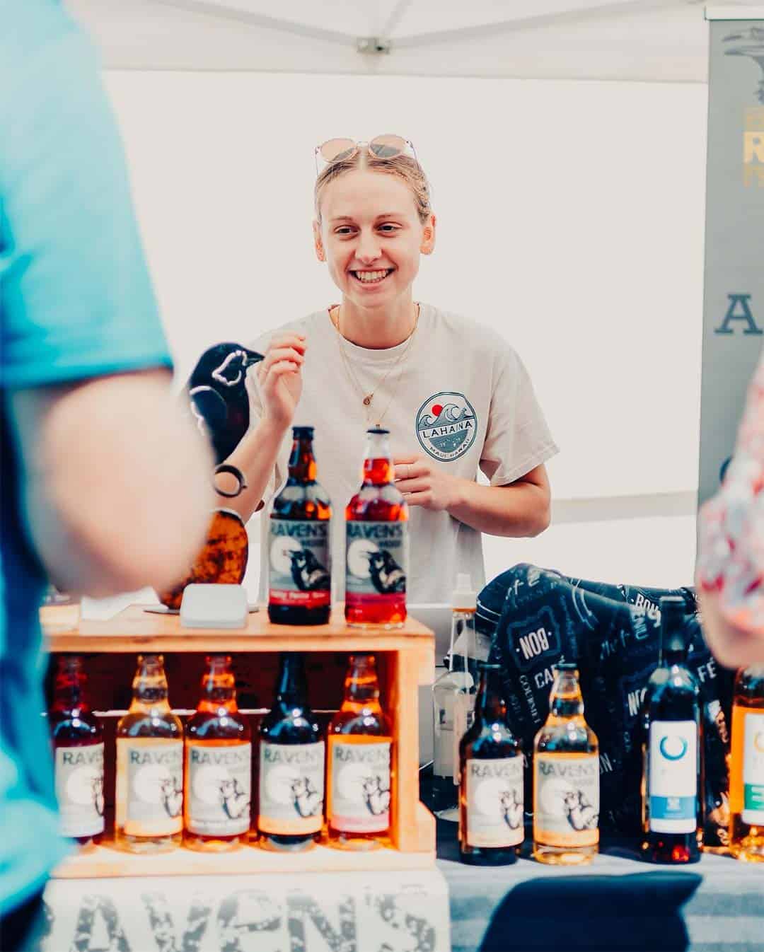 A brewery vendor smiles at a customer behind colourful beer bottles at the farmers market this weekend in Qualicum Beach.