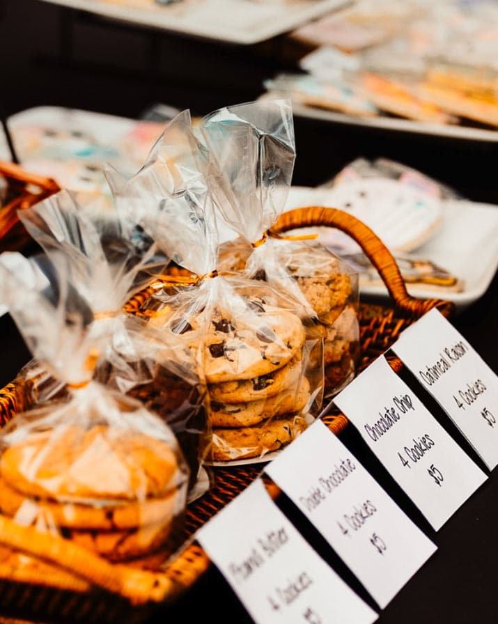 A close up of bags of different types of freshly-baked cookies on a display table at an outdoor farmers market in Qualicum Beach.