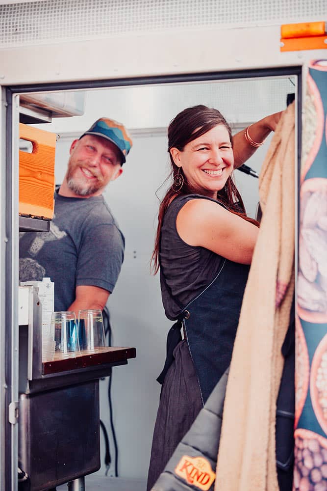 A smiling man and women are seen inside their food truck at the Qualicum amrket.