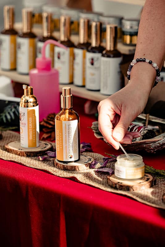 Jars and bags of herbs and jams are seen on a wooden display table at the Qualicum Beach Farmers Market.